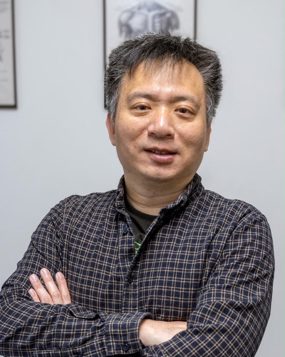 Michael Yan standing with his arms crossed in front of framed anatomy prints