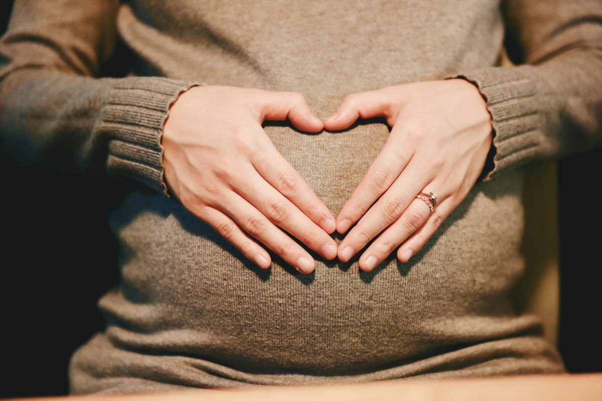 Hands forming a heart over a pregnant belly